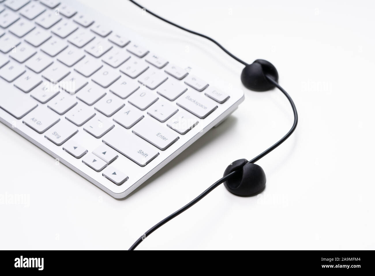 Ordinateur portable blanc adhésif et organisateur de câble isolé sur fond blanc Banque D'Images