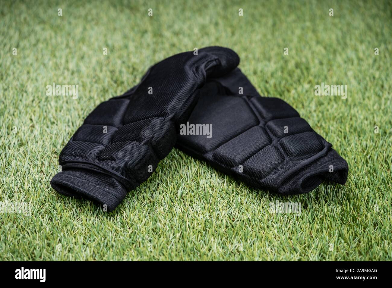 Close-up of Sports de protection noir Jambières sur fond de gazon vert Banque D'Images