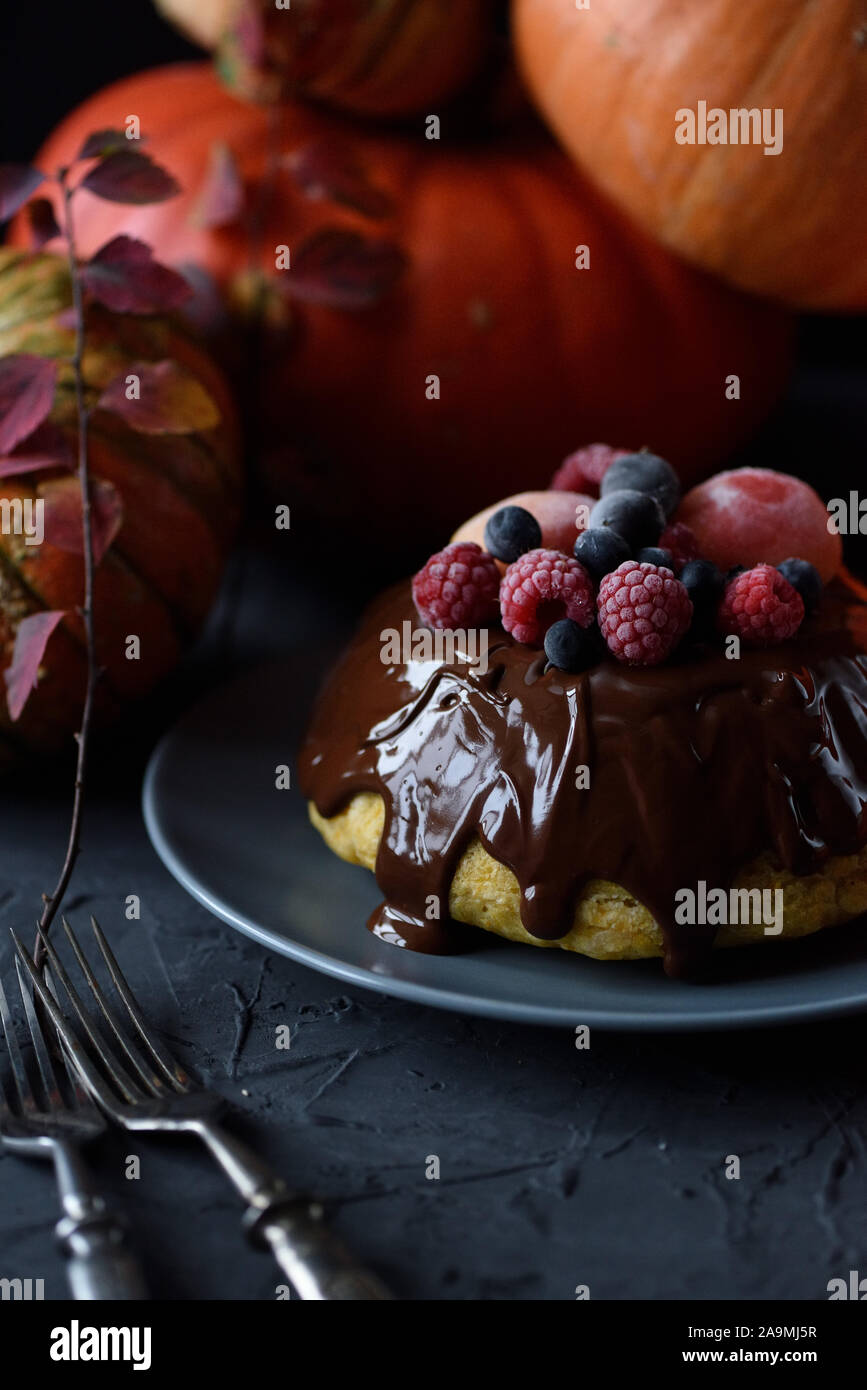Dessert maison saine. Pouding vapeur traditionnel avec lustre de chocolat et de baies et les courges d'hiver sur fond noir copy space Banque D'Images