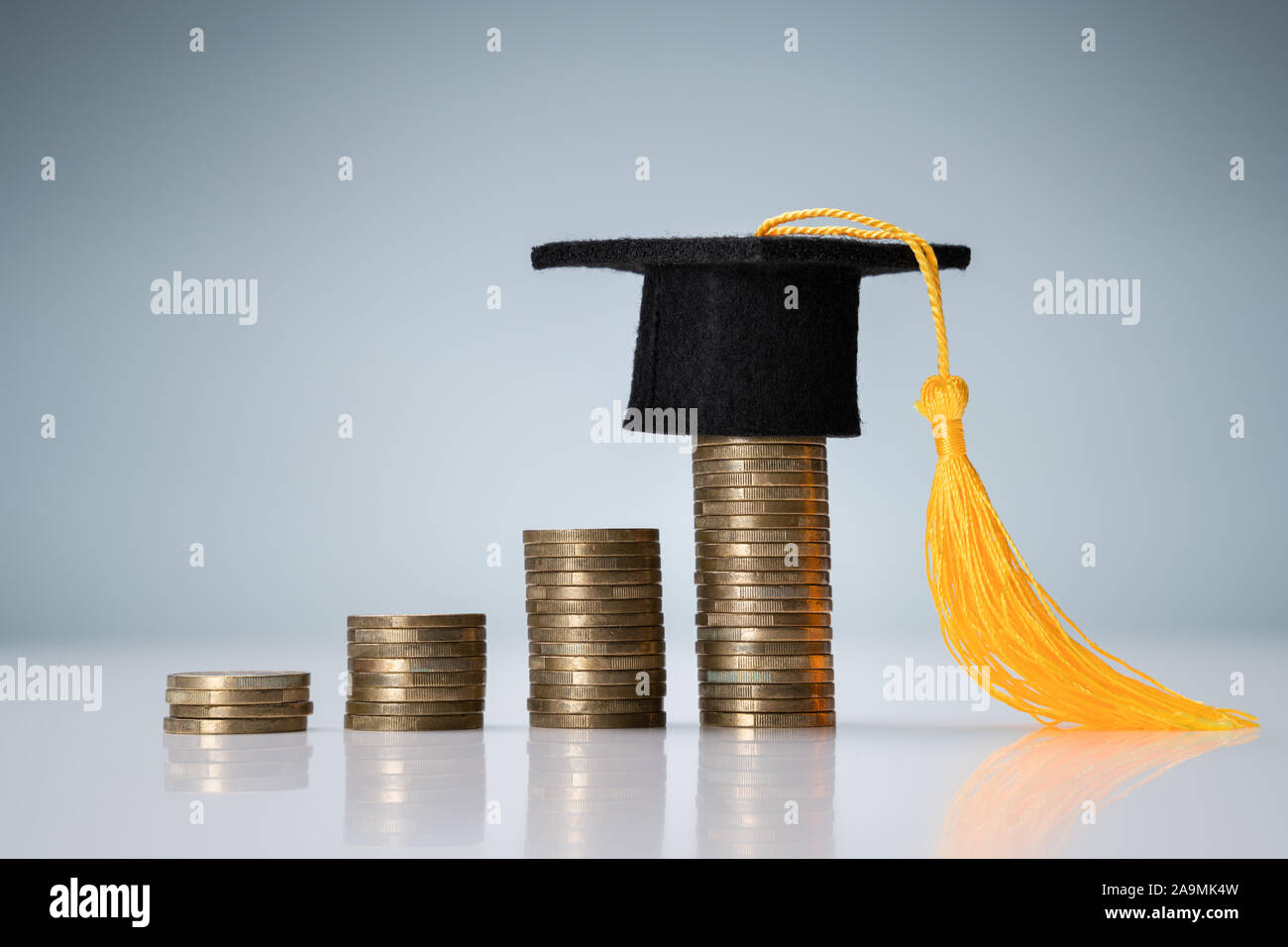 Miniature de Graduation Hat sur le dessus de la pile de pièces de bureau réfléchissant Banque D'Images