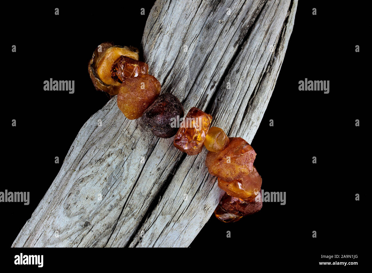 Près d'un bracelet d'ambre naturel brut avec différentes nuances d'orange enroulé autour de la direction générale des anciens en bois avec fond noir Banque D'Images