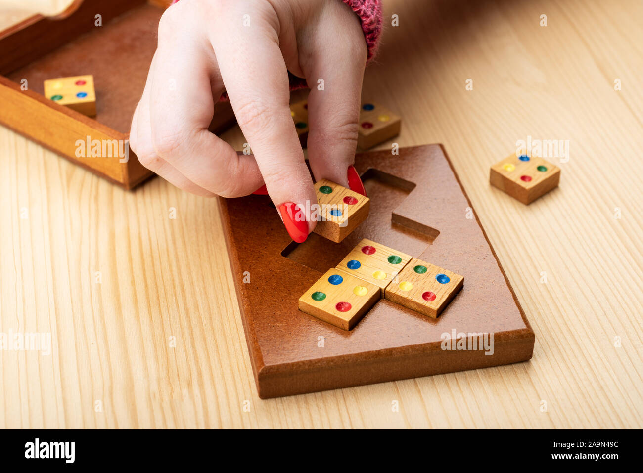 Fille essaie d'assembler un puzzle mosaïque. Manucure lumineux sur les ongles. Puzzles de la catégorie puzzle correspondant edge. Copier l'espace. Concept Puzzle Banque D'Images