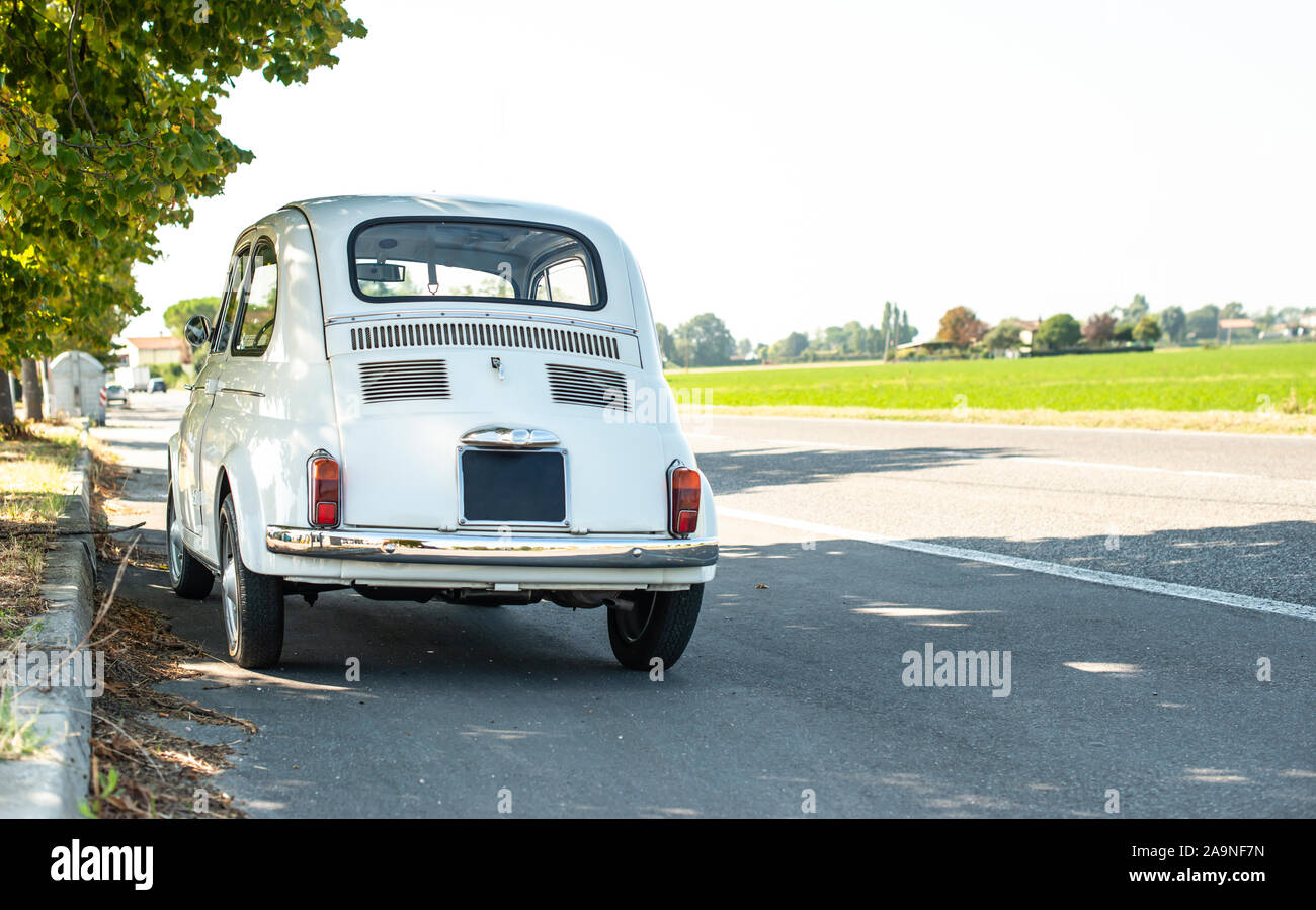 Petit blanc vintage car dans la rue. Pas de personnes. L'asphalte route de village en Italie. Concept de voyage avec voiture. Banque D'Images