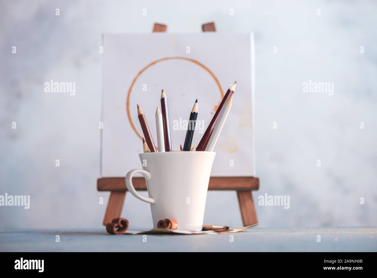Tasse de café avec des crayons à l'avant et de taches de café peinture sur  un chevalet. Créativité en milieu de travail Photo Stock - Alamy