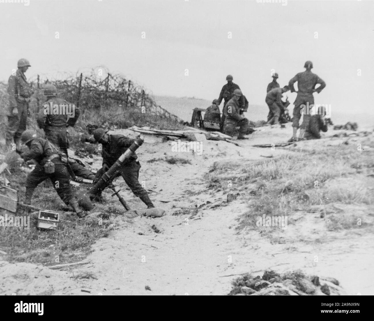 Un équipage de mortier se tient en retrait juste avant de tirer dans une position nazie quelque part le long de la côte normande, en France. Banque D'Images