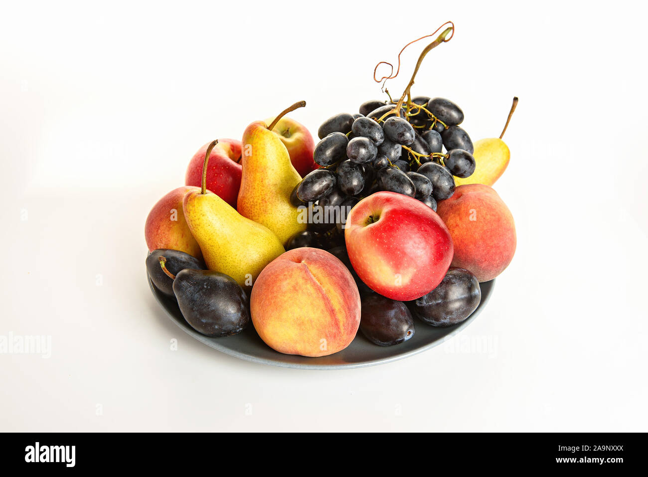 Nature morte avec les bananes, poires, prunes, raisins, pommes et les pêches sur une assiette. Banque D'Images