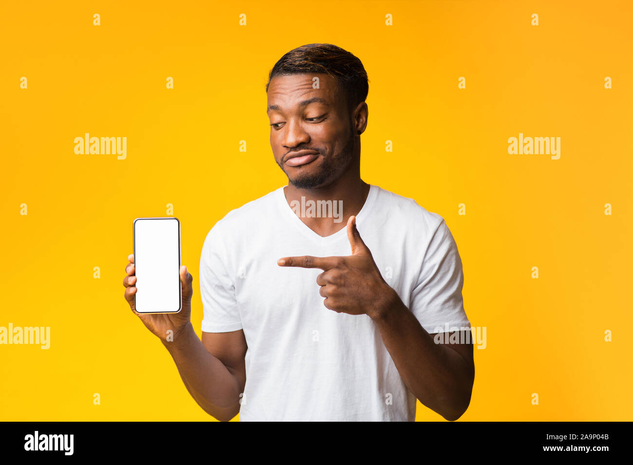 Guy Pointing Finger à l'écran vide de cellulaire, maquette, Studio Shot Banque D'Images