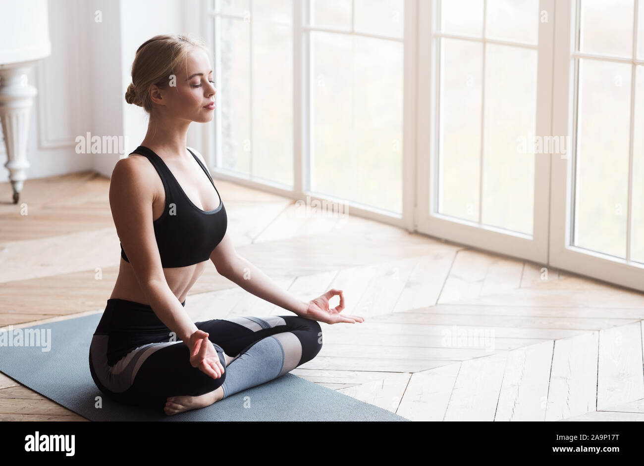 Yoga girl aux yeux clos assis en posture de lotus Banque D'Images