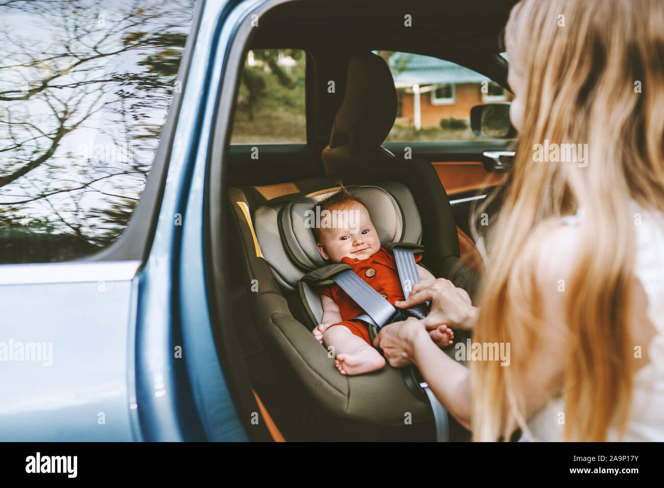Bébé en voiture les ceintures de sécurité de la mère se serre car seat family ville vie vacances voyage routier transport garde d'enfants Banque D'Images