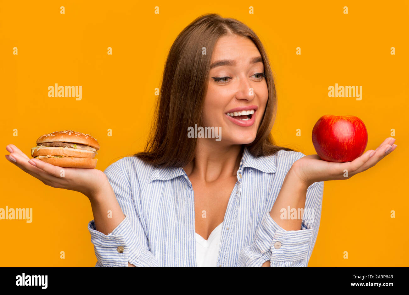 Faim Girl le choix entre Apple et Burger, fond jaune Banque D'Images