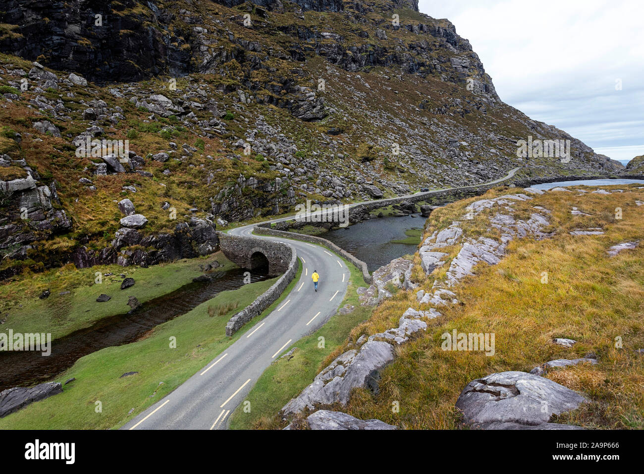 Femme marche par la rivière Loe, route étroite à travers le Gap of Dunloe, niché dans la vallée de Macgillycuddy Reeks montagnes, l'Irlande, le comté de Kerry. Banque D'Images