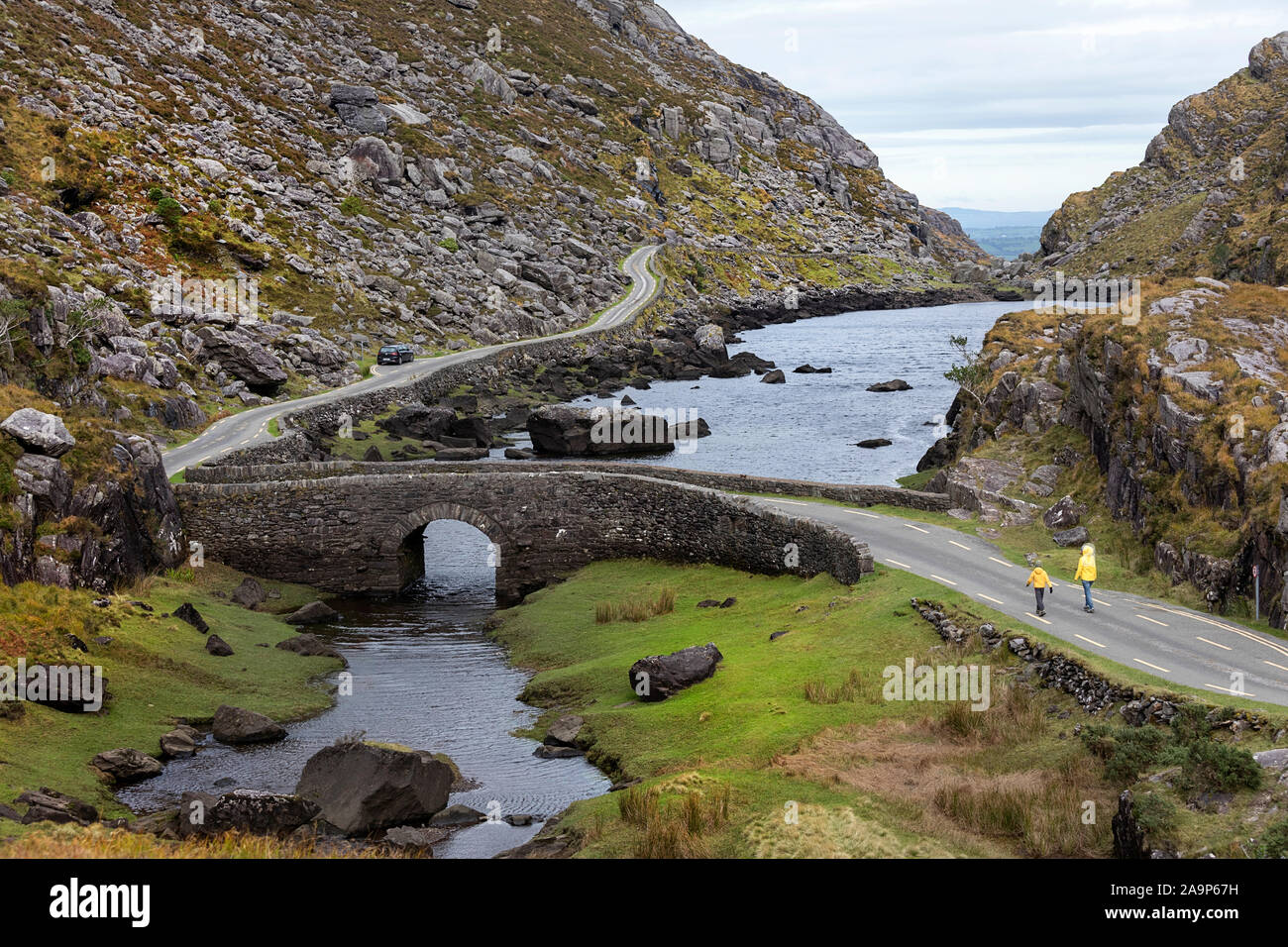 Mère et fils marcher par la rivière Loe, petite route à travers la vallée de Gap of Dunloe Macgillycuddy Reeks dans les montagnes, l'Irlande, le comté de Kerry. Banque D'Images