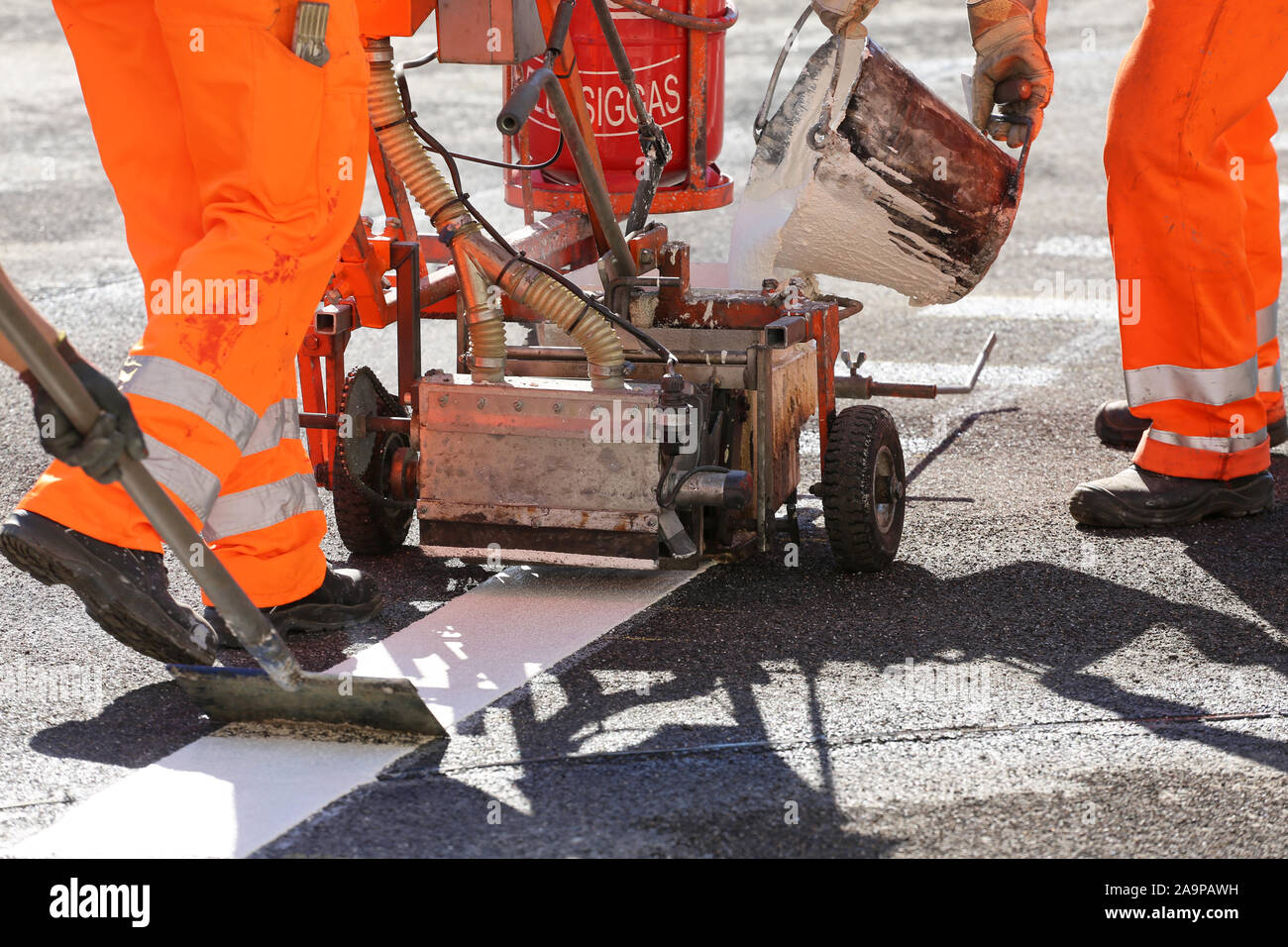 La ligne blanche la peinture sur l'asphalte avec une machine de marquage routier Banque D'Images