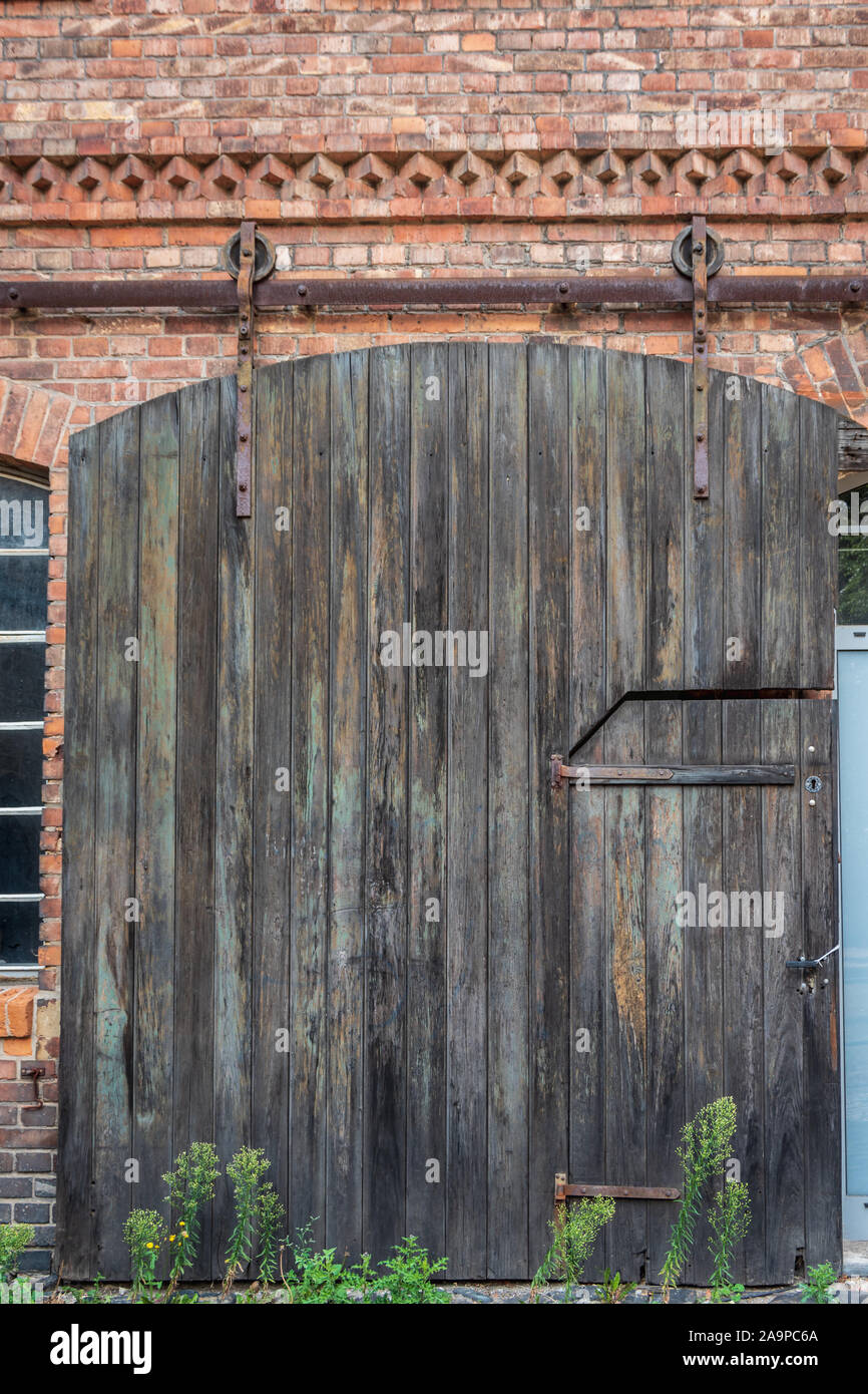 Vue d'un ancien industriel en bois porte coulissante sur une façade en  briques rouges d'un bâtiment. Bracelet Vintage porte. Roue industrielle  porte bois grange d'acier Photo Stock - Alamy