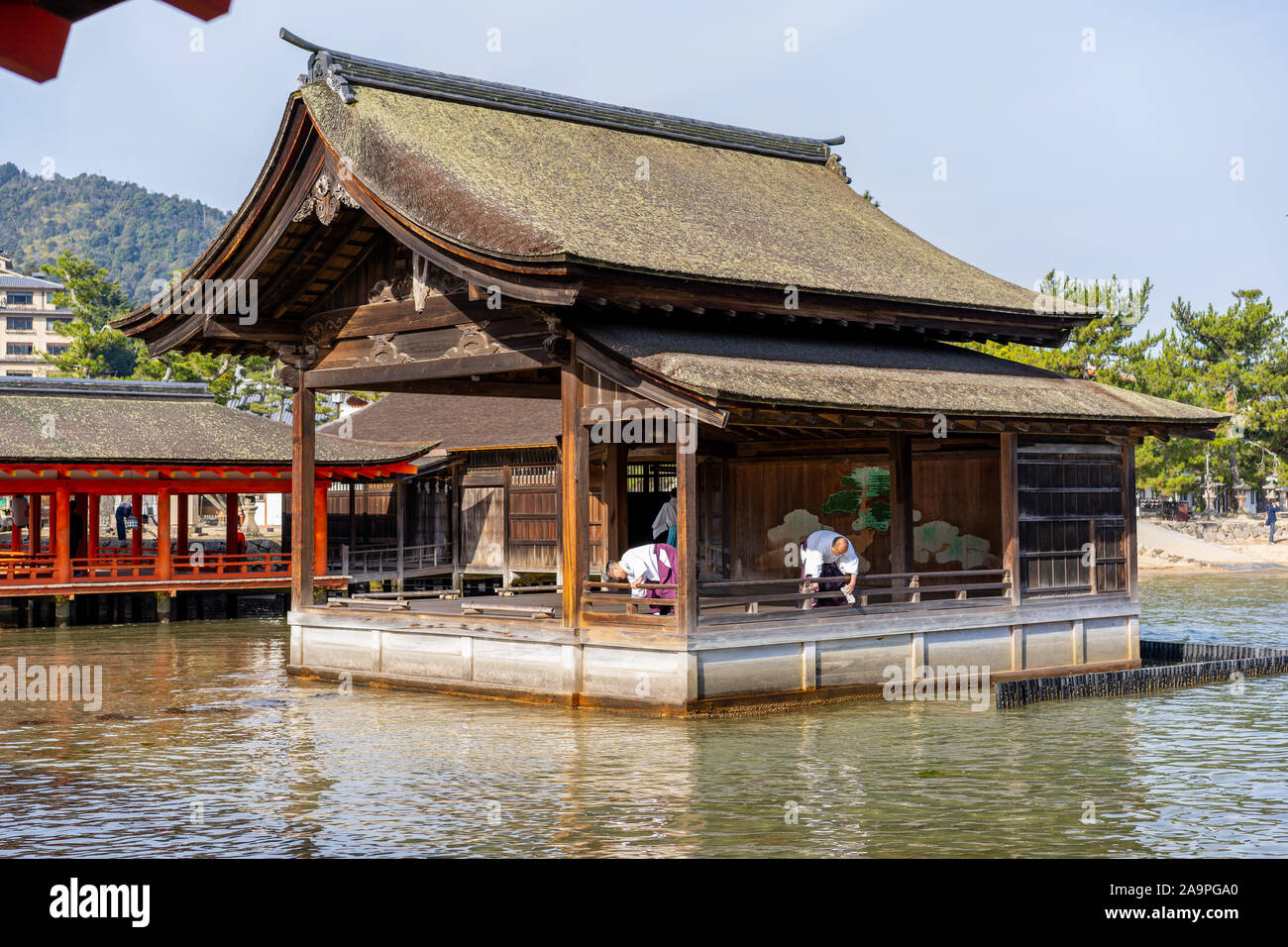Deux Monks nettoyant la scène de théâtre du sanctuaire d'Itsukushima Noh, Miyajima, Japon Banque D'Images