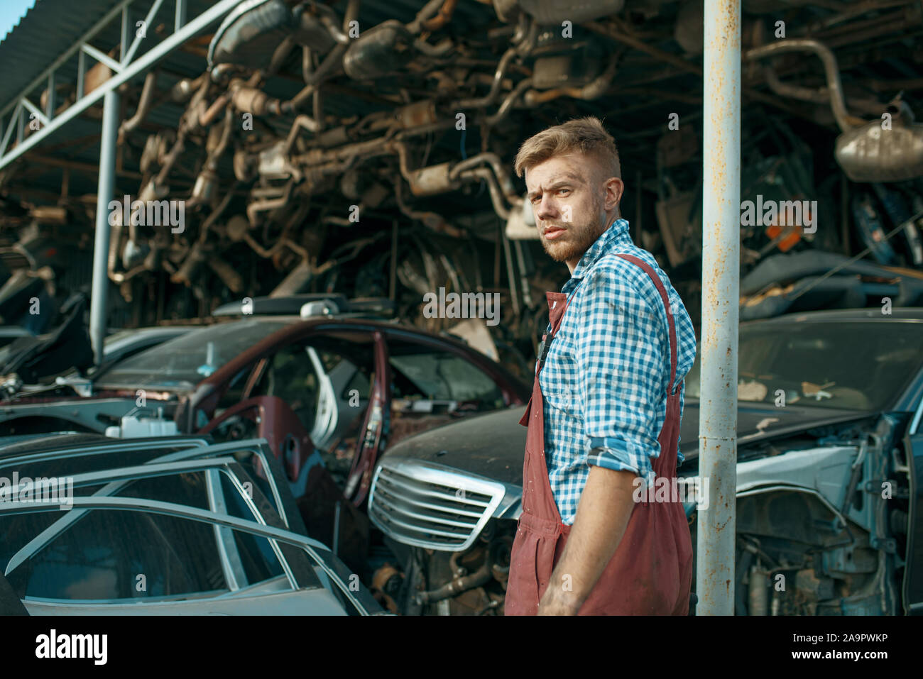 Homme mécanicien à la pile de voitures sur junkyard Banque D'Images