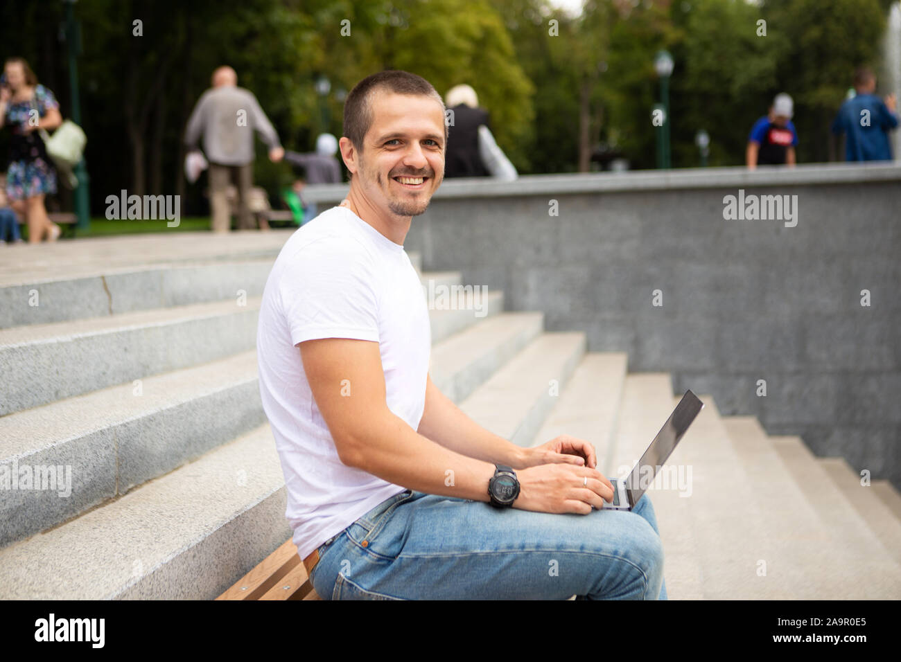 L'homme indépendant avec laptop sitting in urban park Banque D'Images
