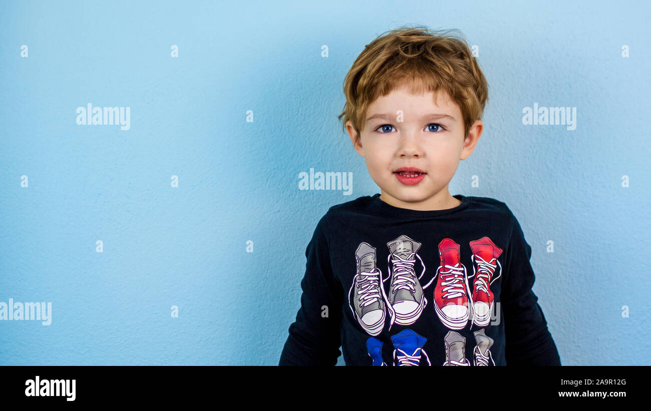 Adorable petit garçon de trois ans de race blanche avec visage Mignon expression sur fond bleu Banque D'Images