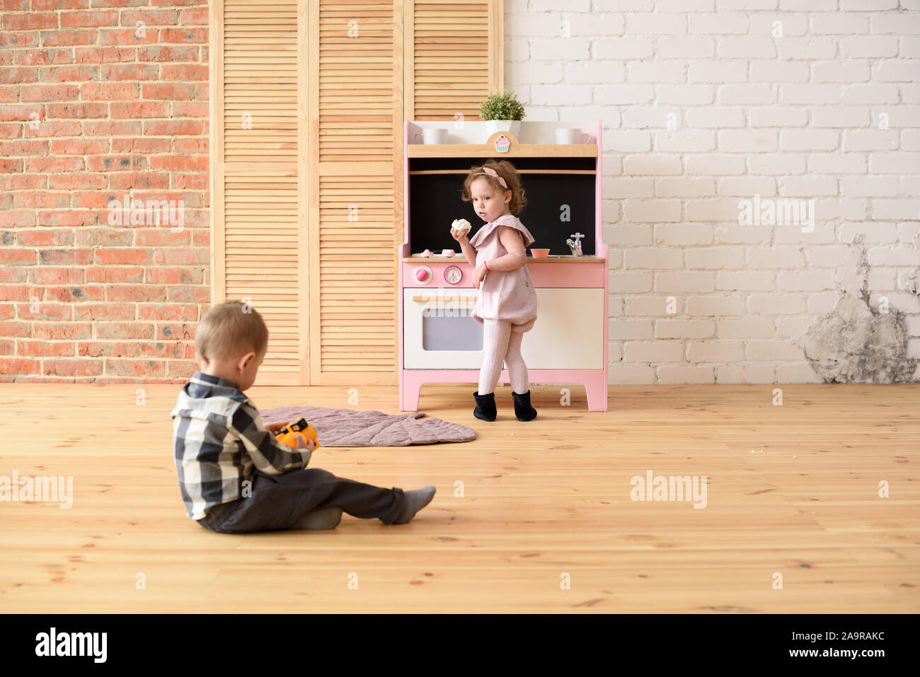 Famille et enfants concept. Bébé Garçon jouant sur marbre et cute little girl eating sweets à jouer à big cuisine salle vide copy space Banque D'Images