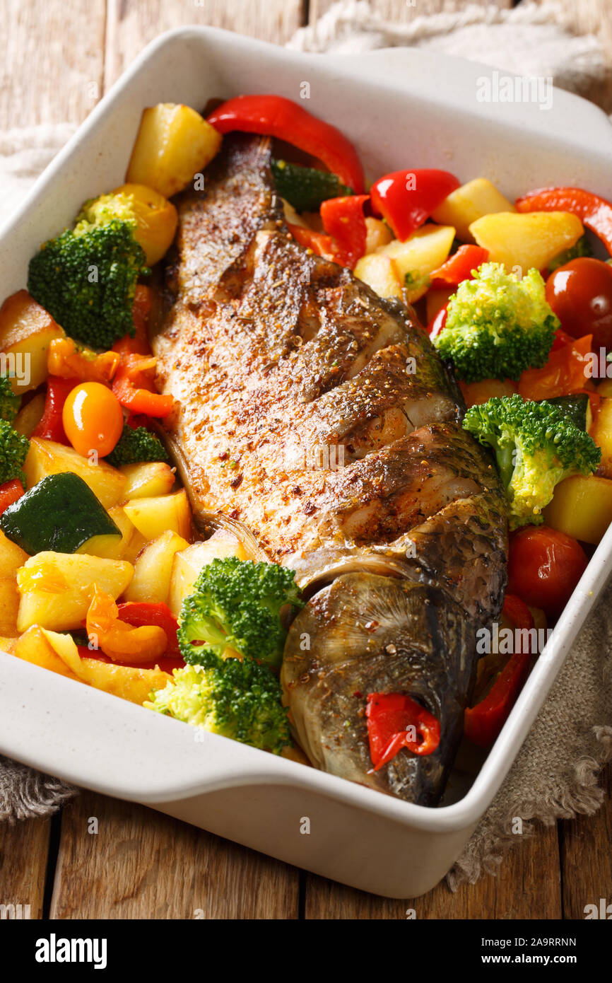 La carpe au four avec légumes close-up dans un plat allant au four, sur la table verticale. Banque D'Images