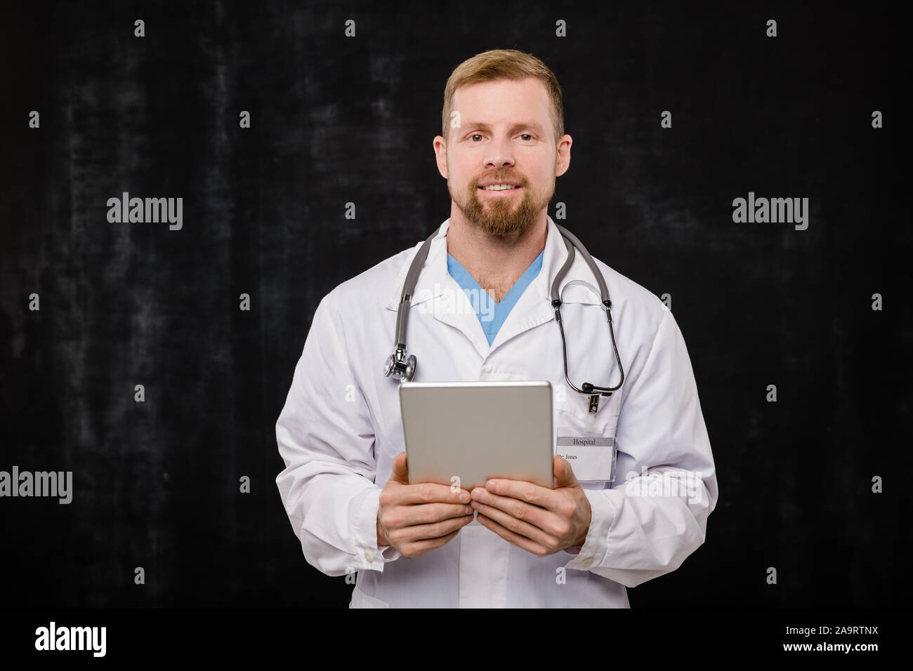 Jeune médecin barbu dans blanchon holding digital tablet par ceinture Banque D'Images