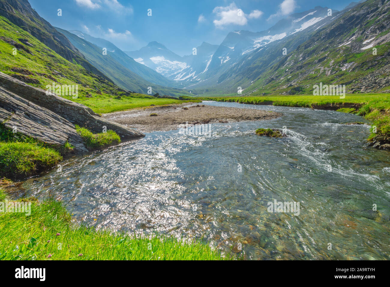 Alpine luxuriante vallée avec ruisseau glaciaire découlant de la fonte des glaces et de la neige sur les montagnes environnantes. Paysage de montagne idyllique. Banque D'Images