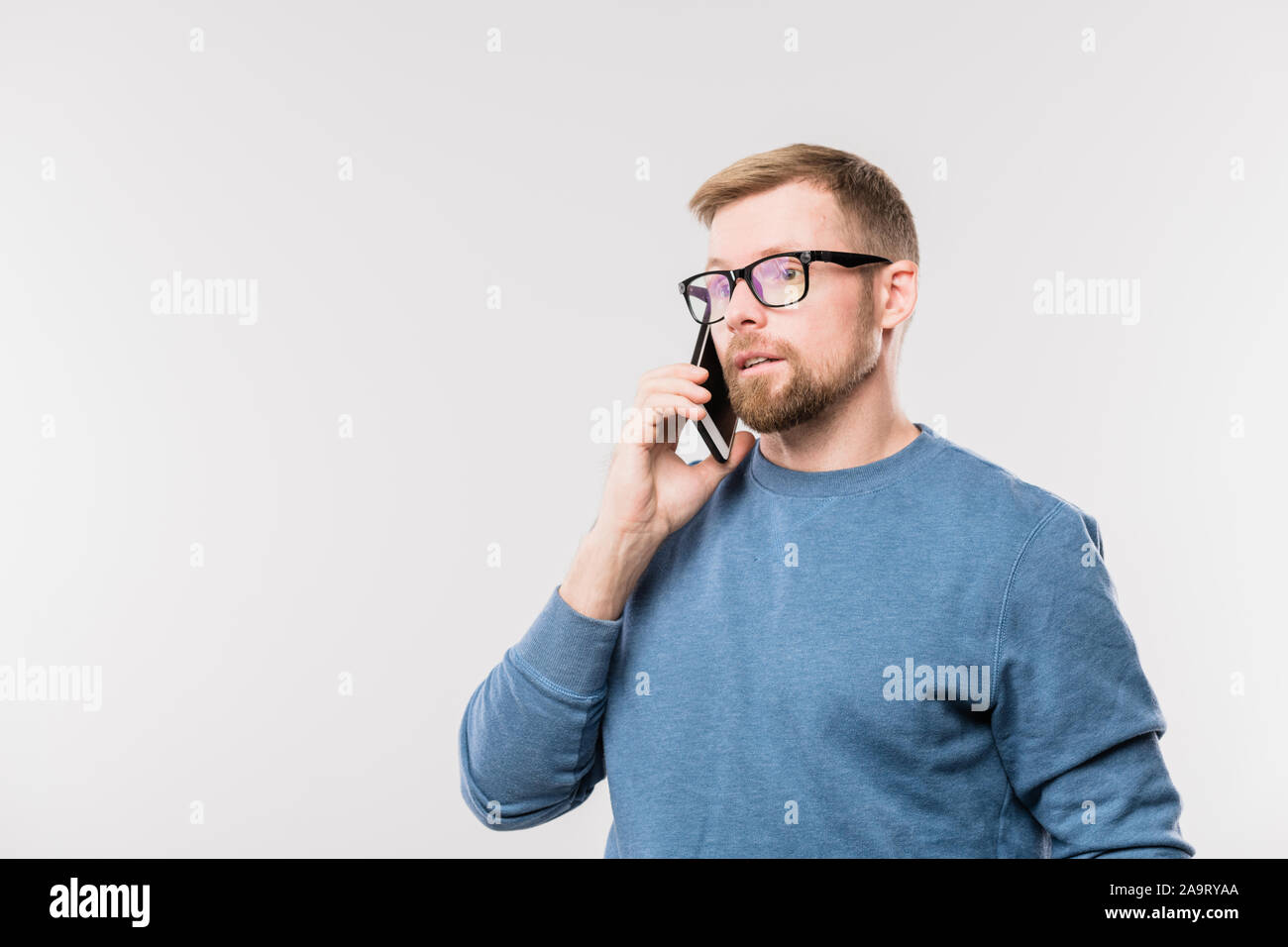 Les jeunes agent barbu holding smartphone par l'oreille, tout en parlant à l'un de clients Banque D'Images