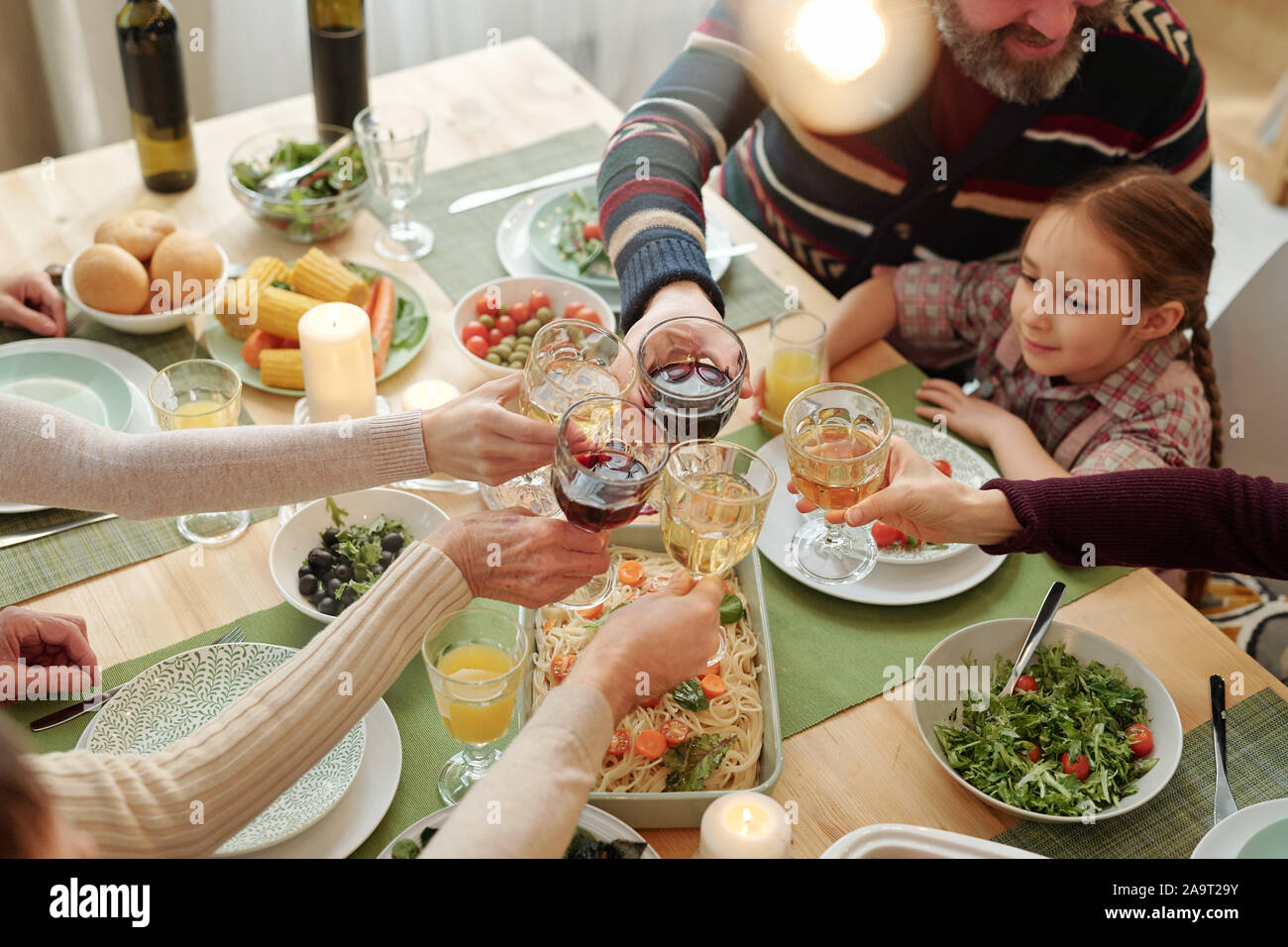 Mains de famille de six de trinquer avec un verre sur table de fête cuisine maison Banque D'Images