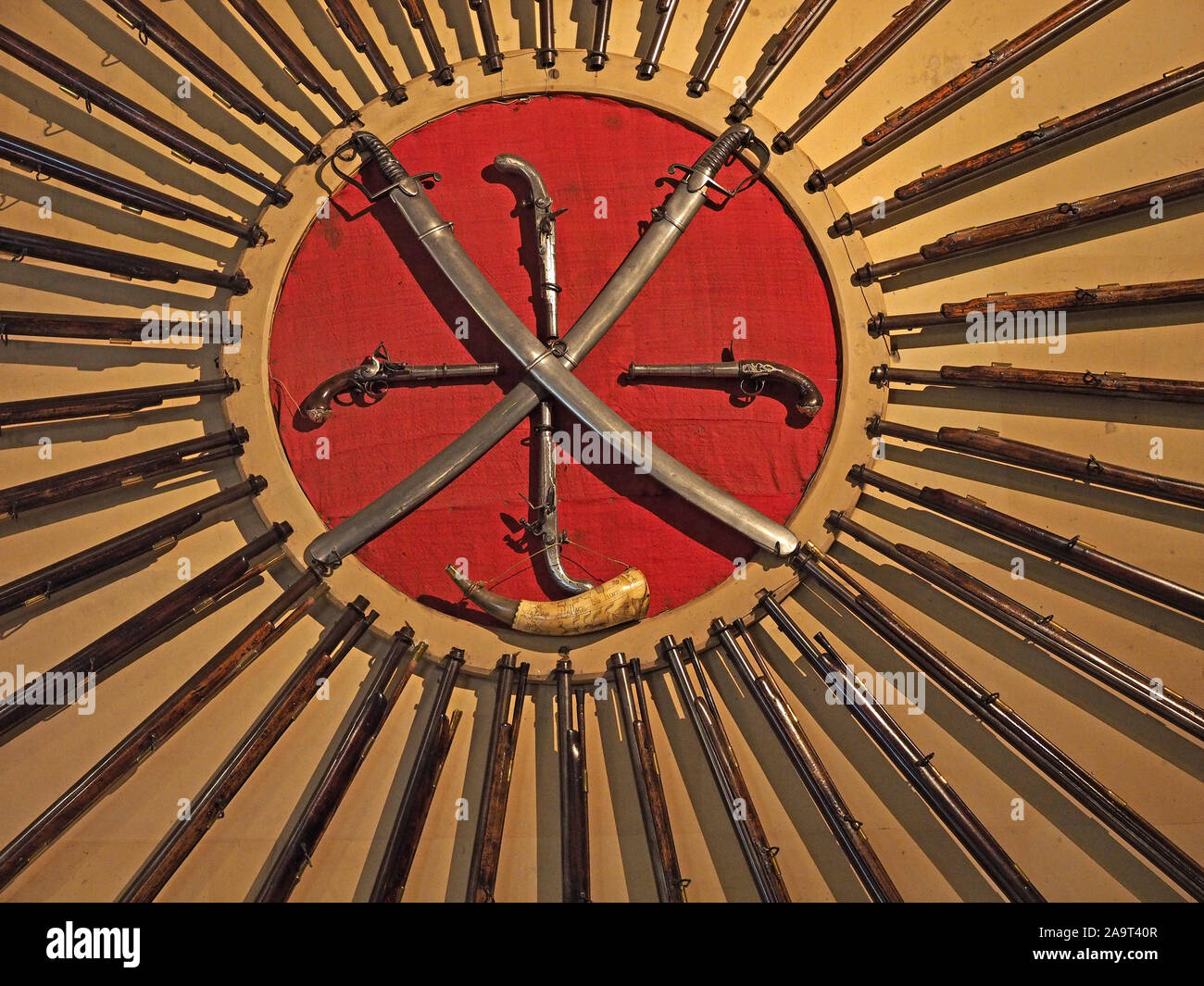 Volant de nombreux barils fusil entourent un cercle rouge traversé avec épées gainées & pistolets antiques avec corne à poudre créer radiales England, UK Banque D'Images