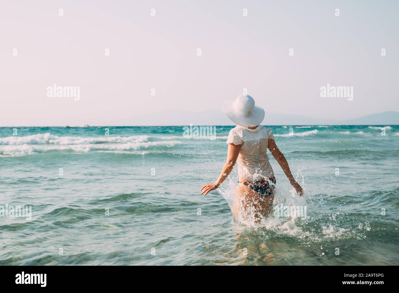 Lady Young Caucasian Woman in Swimsuit et été Hat marche dans la mer. Locations sur mer océan plage. Banque D'Images