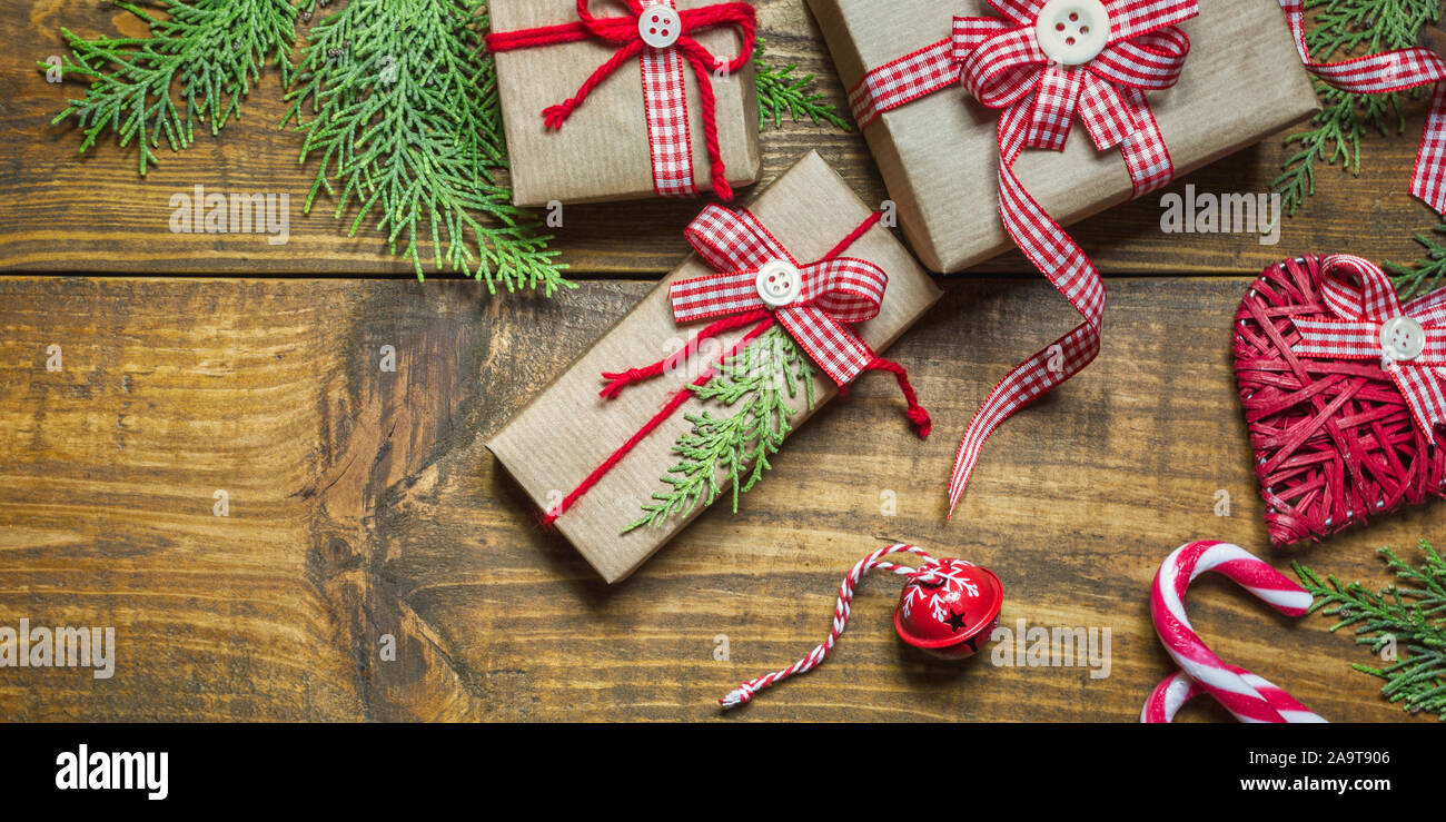 Composition de Noël cadeaux faits à la main, enveloppé dans du papier craft, des branches, des décorations et des cannes de bonbon sur la table en bois rustique. Noël ou Nouvel Banque D'Images