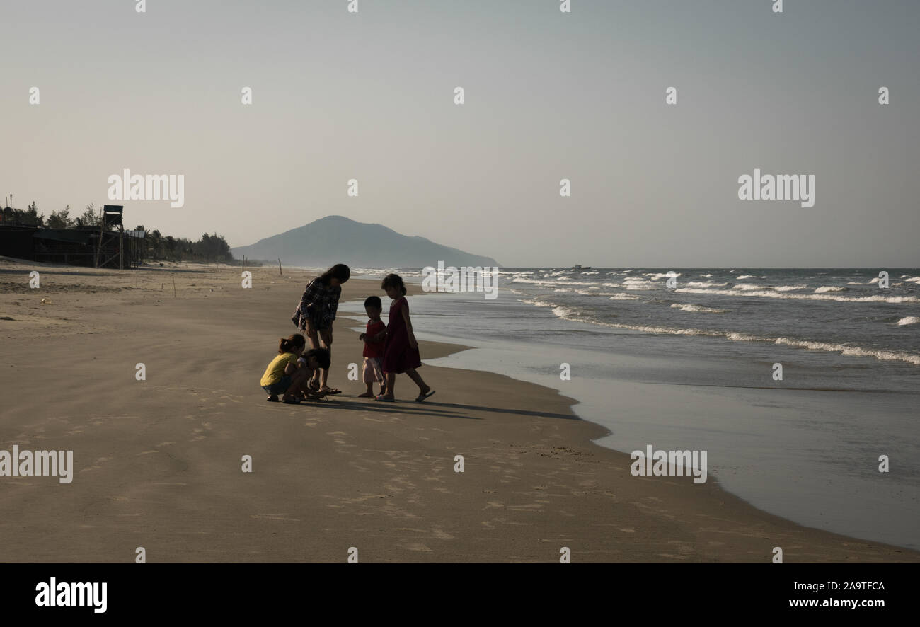 Les jeunes enfants vietnamiens jouer ensemble à large et vide la plage Lang Co., Vietnam Banque D'Images