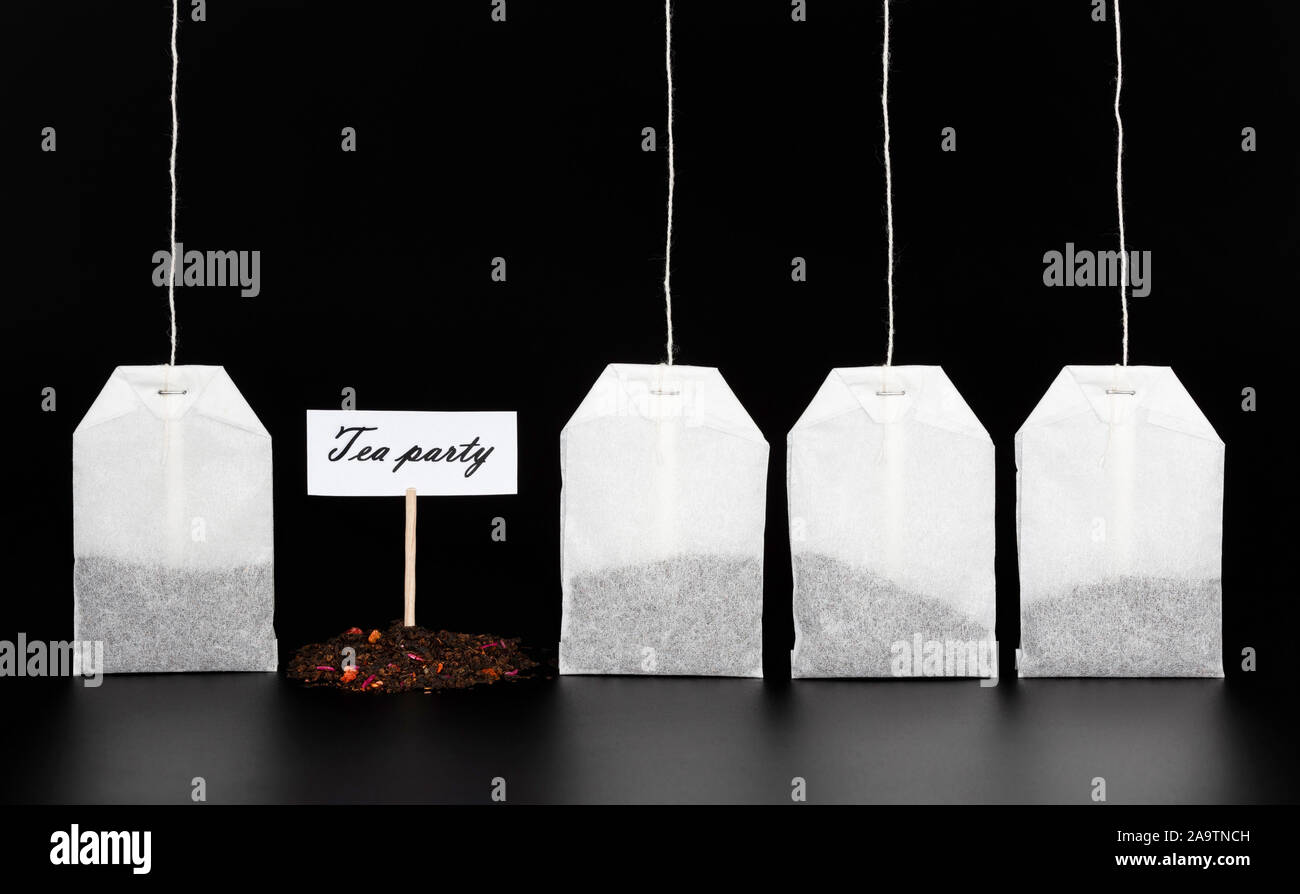 Quatre sachets de thé et d'une diapositive de thé sec avec le signe 'Tea Party' sur un fond sombre. Le concept de boire du thé, cérémonie du thé. Banque D'Images