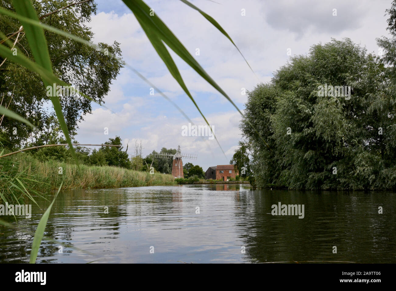 Belle Norfolk classique bazin (moulin) à côté d'un vieux chalet sur un coude de la rivière paisible ; saules de la banque et de l'eau se précipite drapped acros Banque D'Images