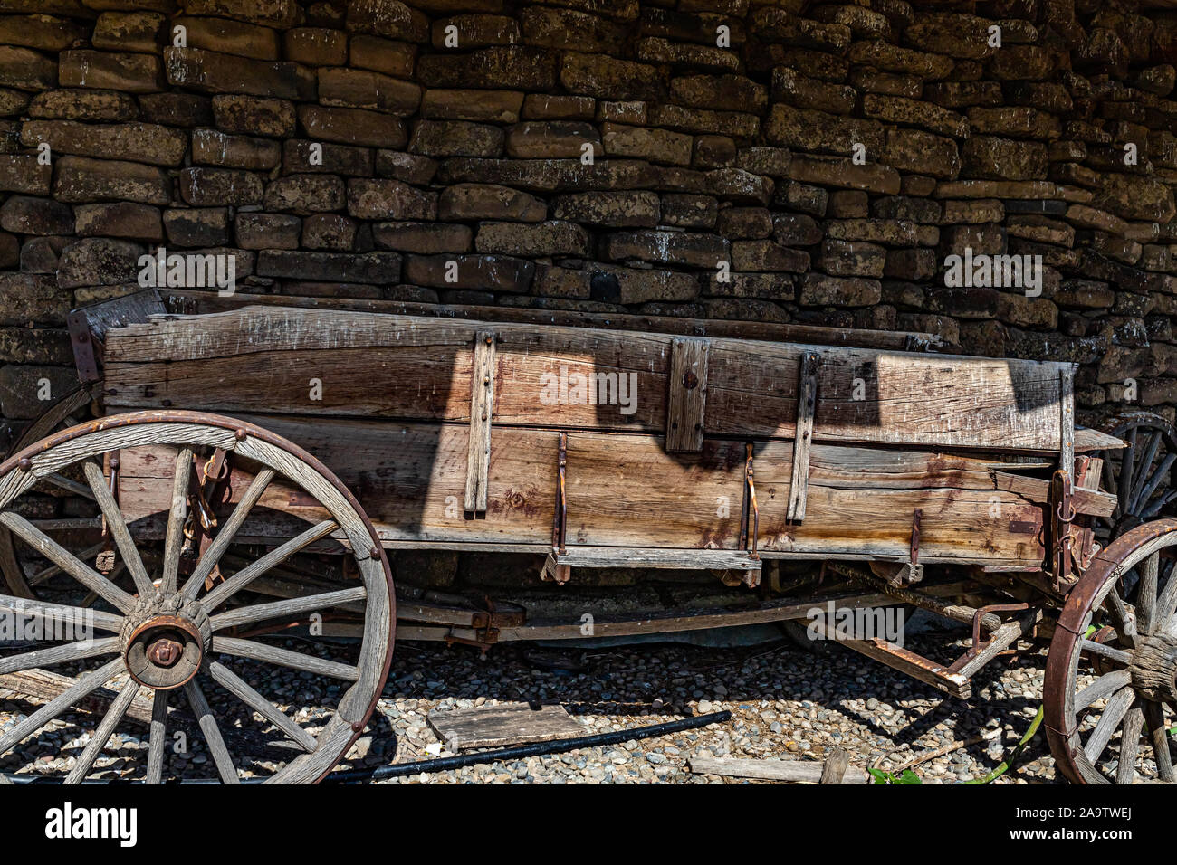 Une ancienne ferme buckboard wagon se trouve en face d'un mur de pierre dans le sud de l'Idaho. Banque D'Images