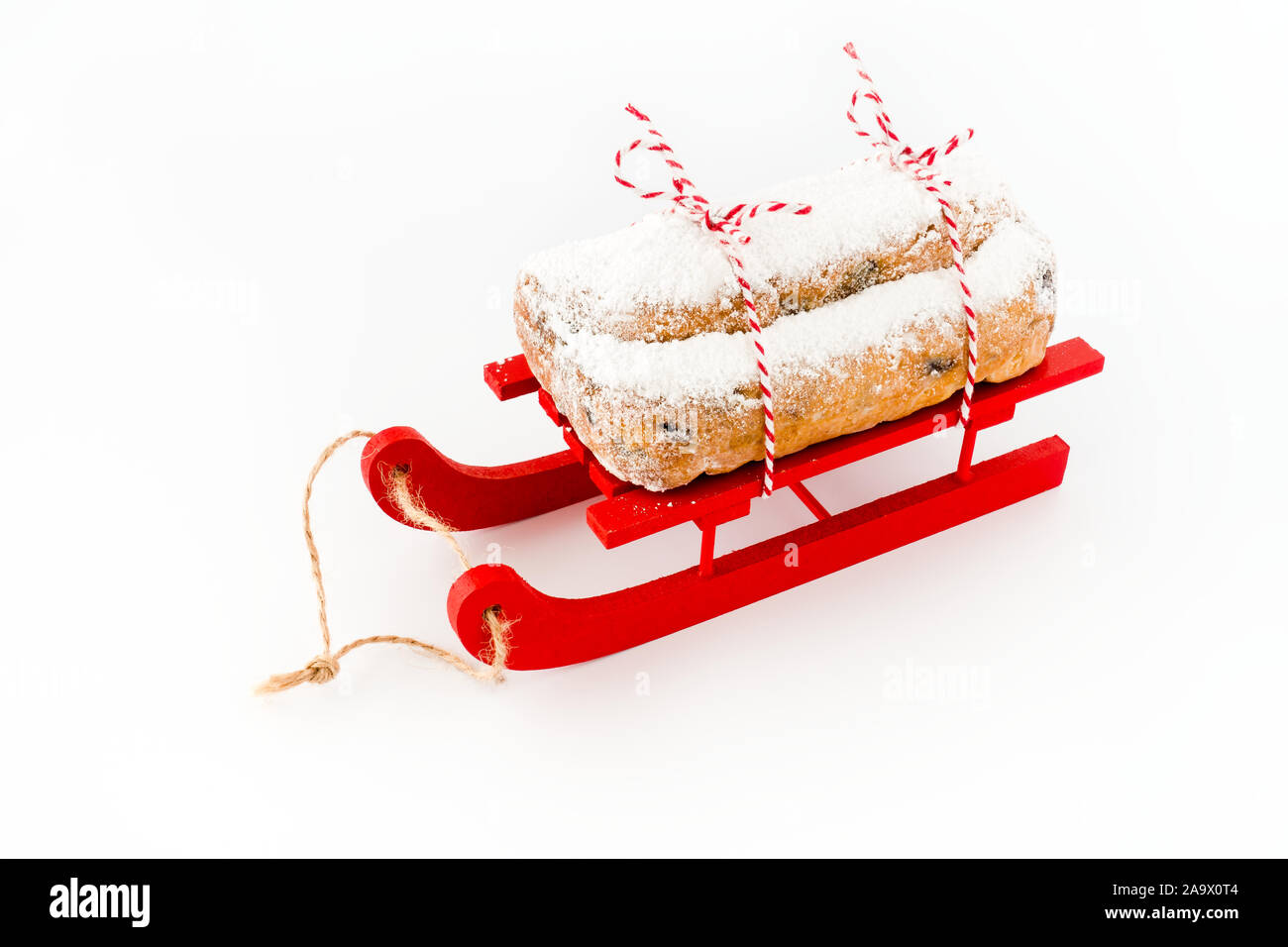 Close-up of Stollen, un Allemand Christstollen, sur traîneau en bois rouge isolé sur blanc. High angle view. Banque D'Images