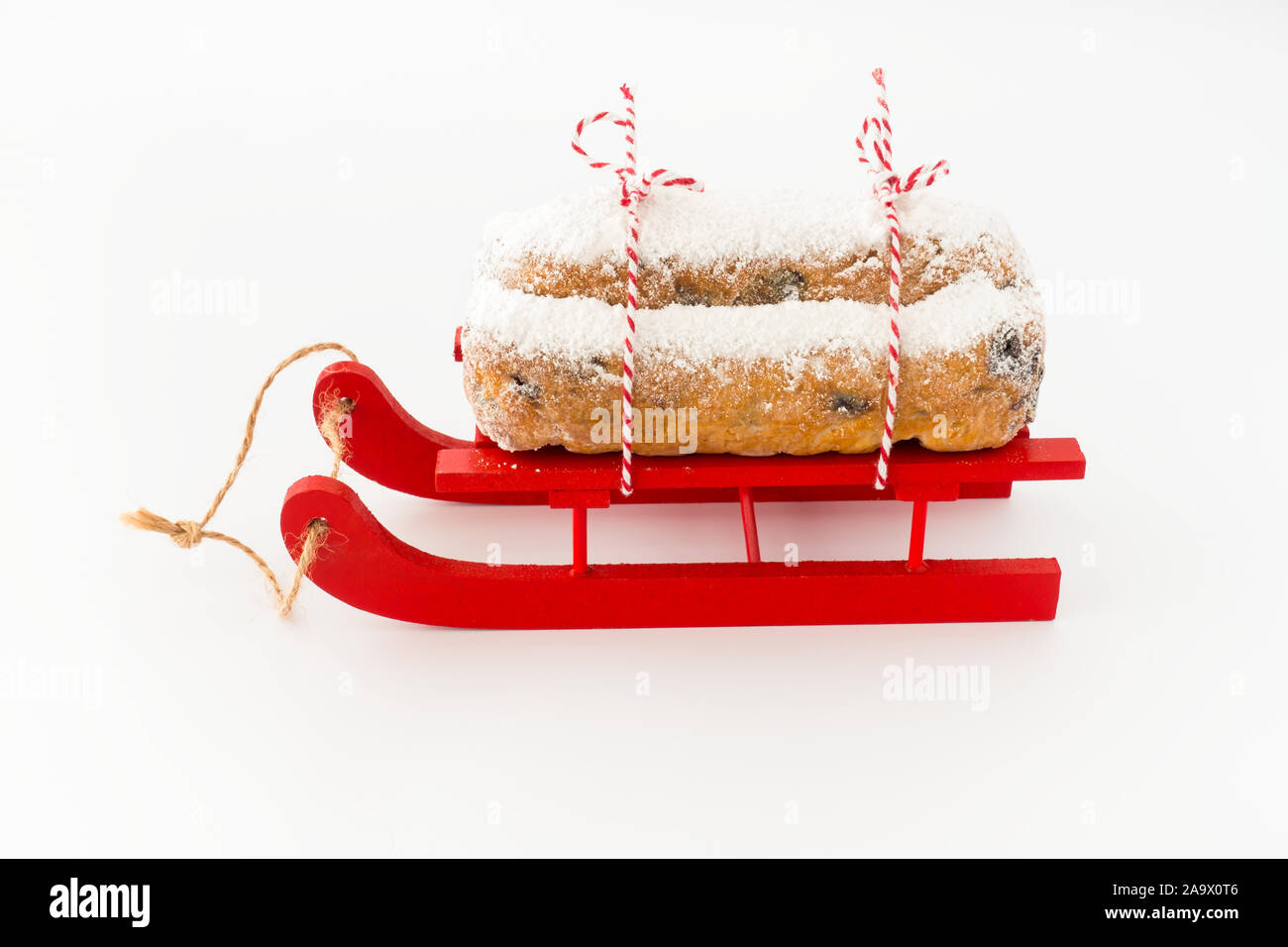 Close-up of Christstollen, un stollen allemand, le traîneau en bois rouge isolé sur blanc. Vue oblique basse. Banque D'Images