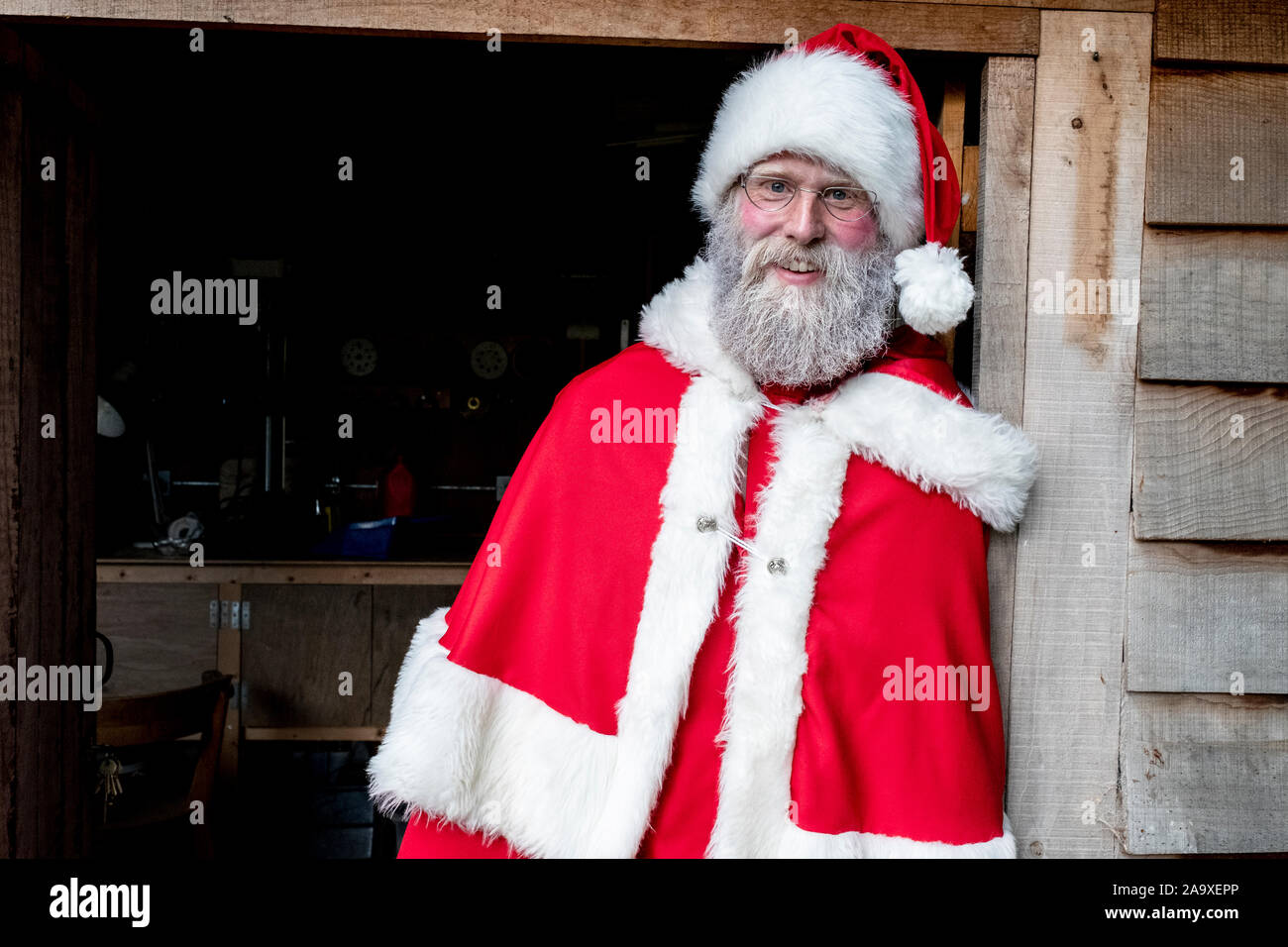Homme portant un costume de Père Noël à l'atelier permanent de la porte, regardant la caméra. Banque D'Images