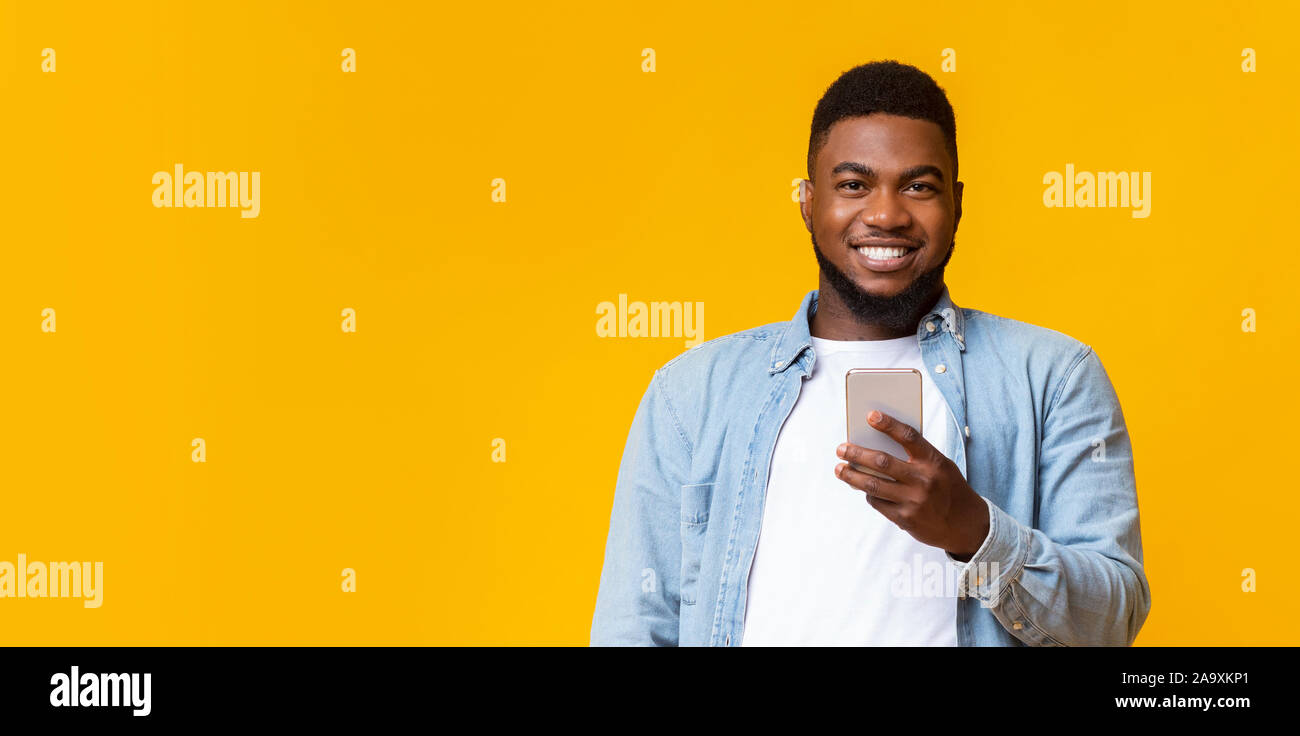 Portrait of smiling black guy avec le smartphone en mains Banque D'Images