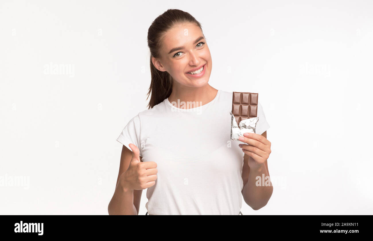 Girl Holding Chocolate Gesturing Thumbs Up Debout, Studio Shot Banque D'Images