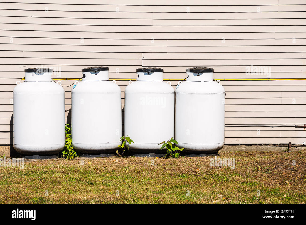 Rangée de bouteilles de propane blanc le long du mur arrière d'une maison Banque D'Images