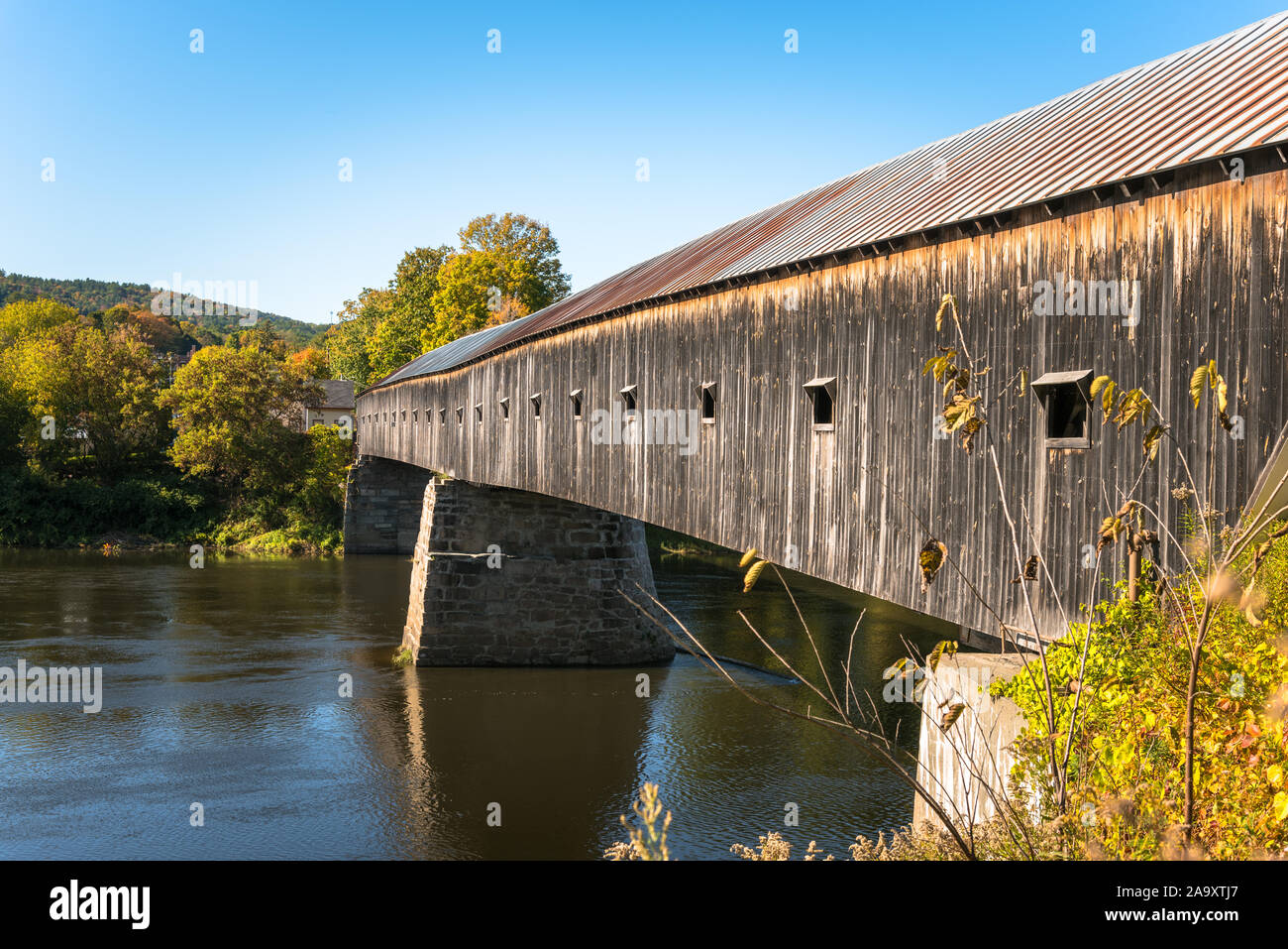 Pont couvert en bois enjambant une rivière sur une claire journée d'automne. Cornish, NH, USA. Banque D'Images