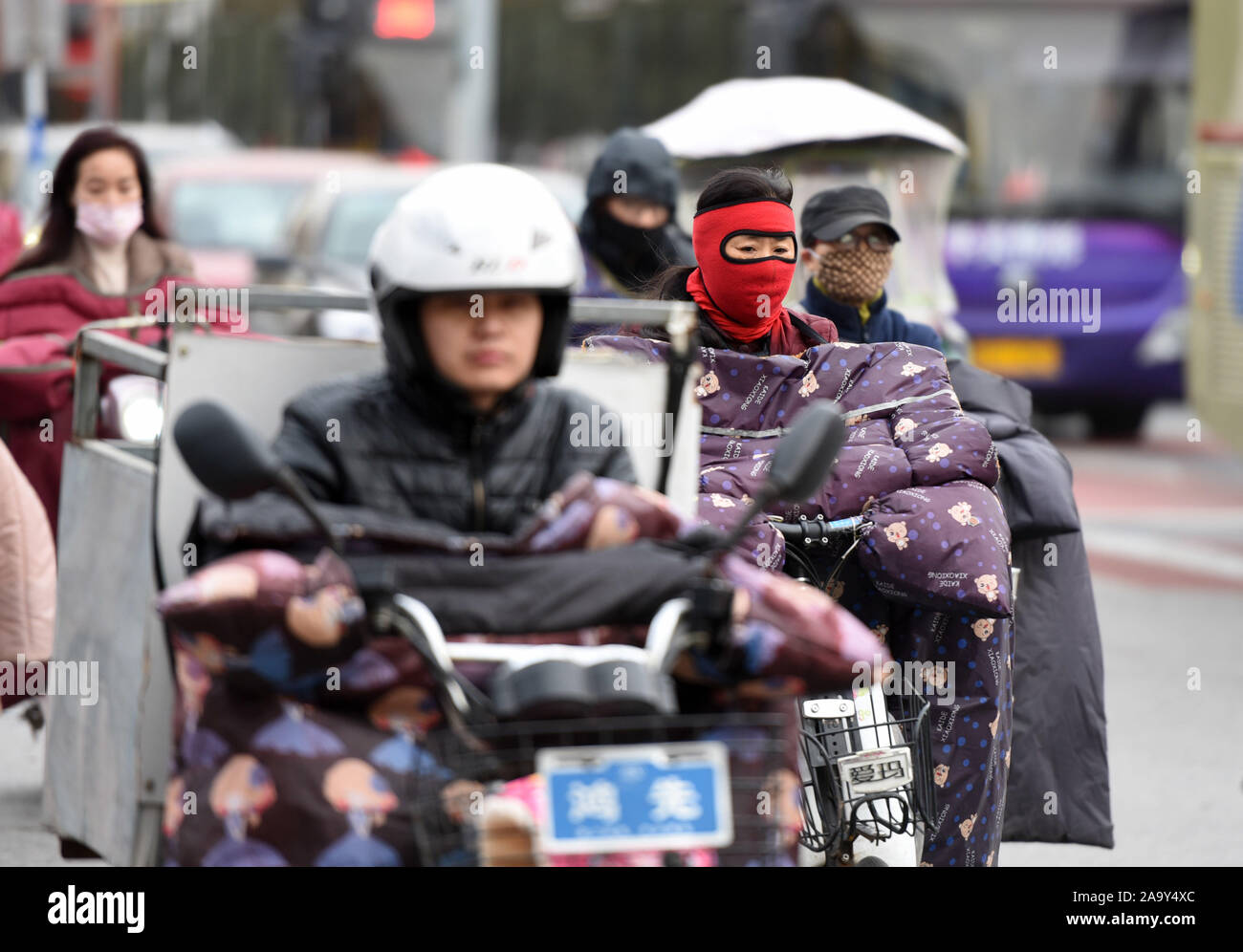 Les résidents locaux chinois portant des vêtements épais les déplacements en vélo électrique sur la route dans la vague de froid dans la région de Huai'an City, province de Jiangsu est sur Banque D'Images