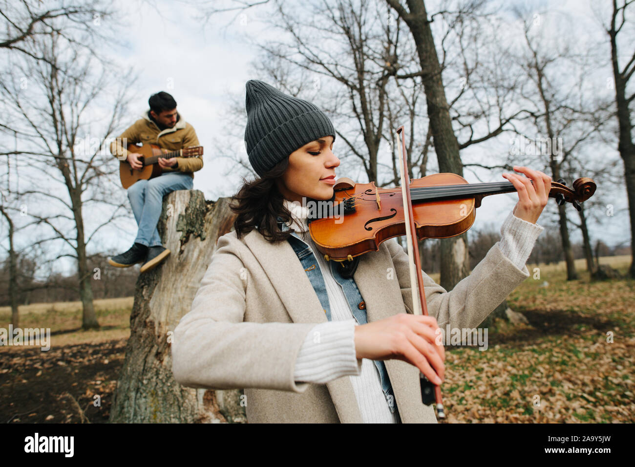 Duo d'un violoniste et guitariste joue de la musique dans une belle forêt d'automne Banque D'Images