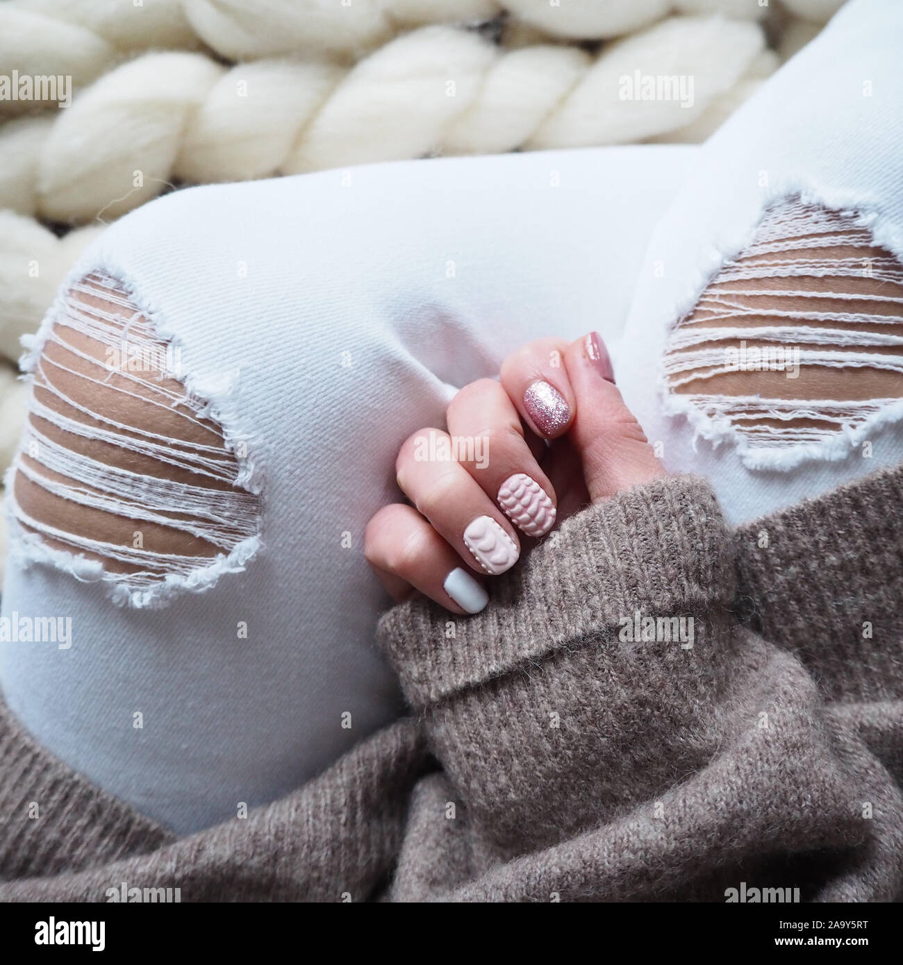 Les femmes avec le pantalon en Jean blanc déchiré montre des ongles avec  des paillettes roses. Manucure française Photo Stock - Alamy