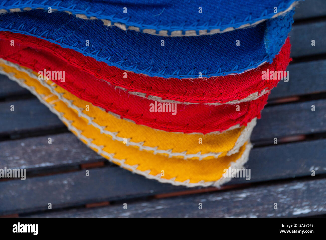 Une pile de tissu coloré chaussures jaune, rouge, bleu sur une table en bois Banque D'Images
