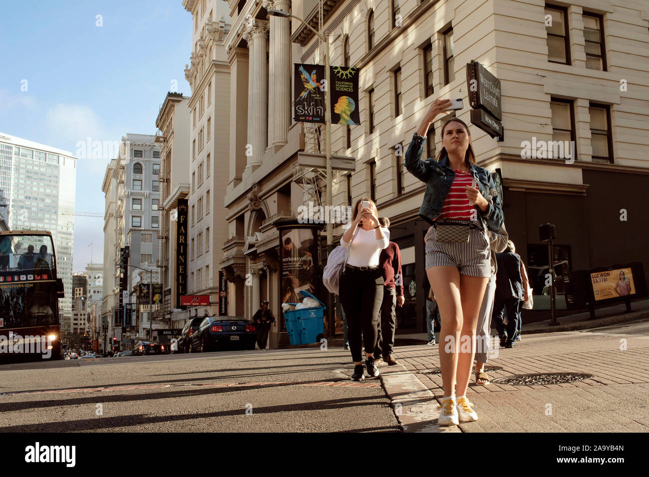 Les femmes prenant des photos avec des téléphones portables alors qu'ils traversent la route sur Bush Street, le centre-ville de San Francisco, Californie, USA. Sep 2019 Banque D'Images