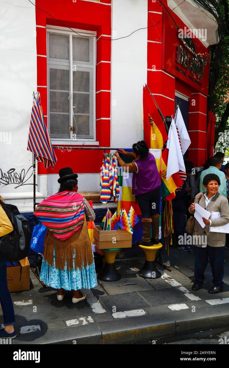 La Paz, Bolivie, 18th octobre 2019. Une femme installe une cabine vendant des drapeaux wipala à un coin de rue à centra la Paz. La Bolivie a tenu des élections présidentielles le 20th octobre, une enquête ultérieure de l'OEA a confirmé un grand nombre d'irrégularités et le président Evo Morales a démissionné le 10th novembre. Au cours des manifestations, quelques drapeaux de wiphala (qui sont un symbole du peuple indigène andin) ont été incendiés, ce qui a conduit à de grandes marches de protestation exigeant que le wiphala soit respecté. Banque D'Images
