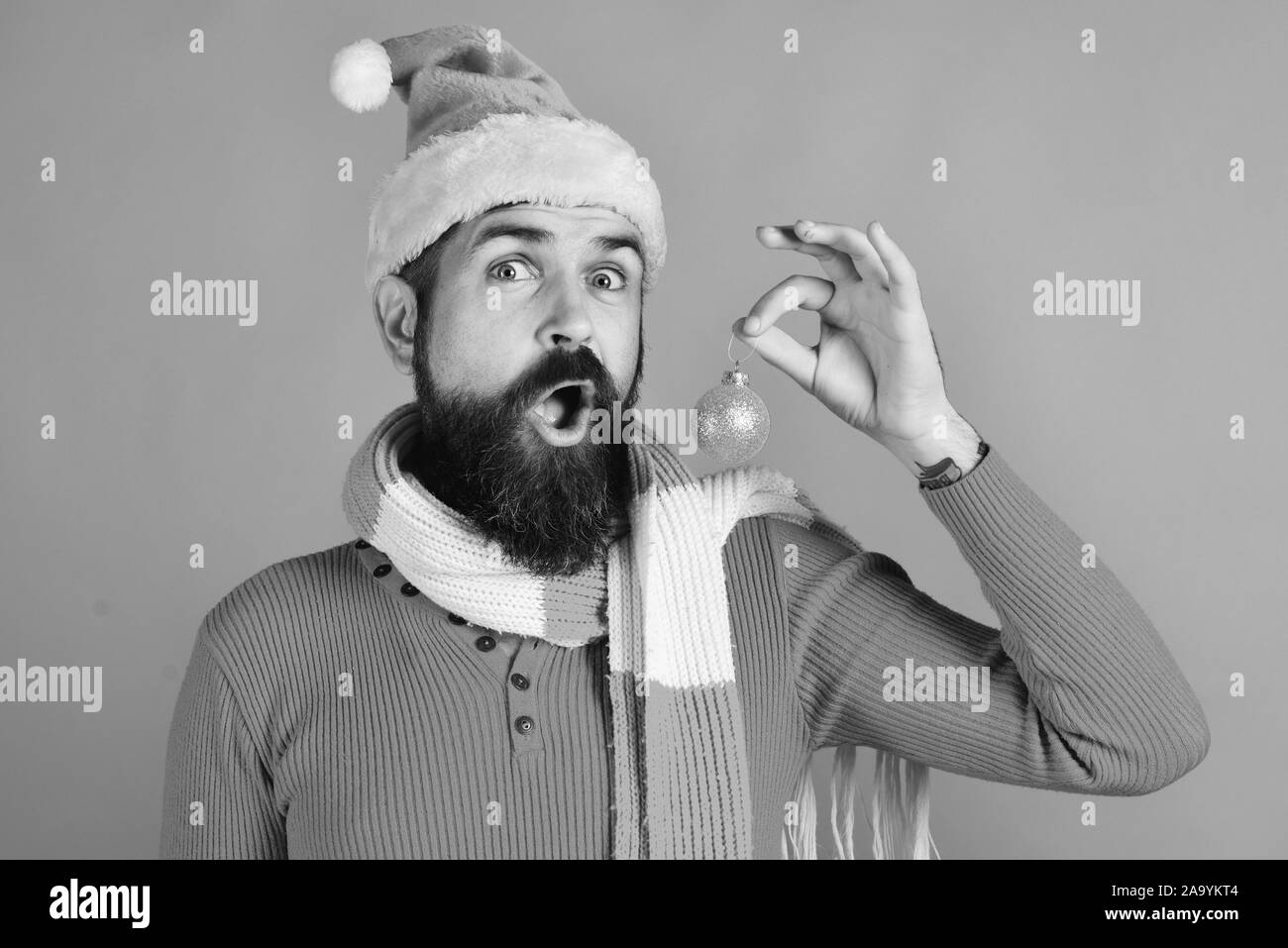 Jeune mec drôle avec rouge santa hat et golden Boule de Noël sur fond rouge Banque D'Images