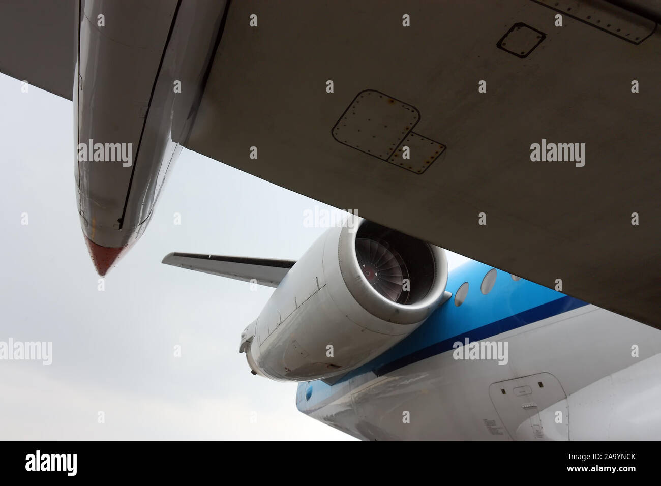 Vue de dessous l'aile d'un gros avion blanc et bleu avec moteur à réaction Banque D'Images